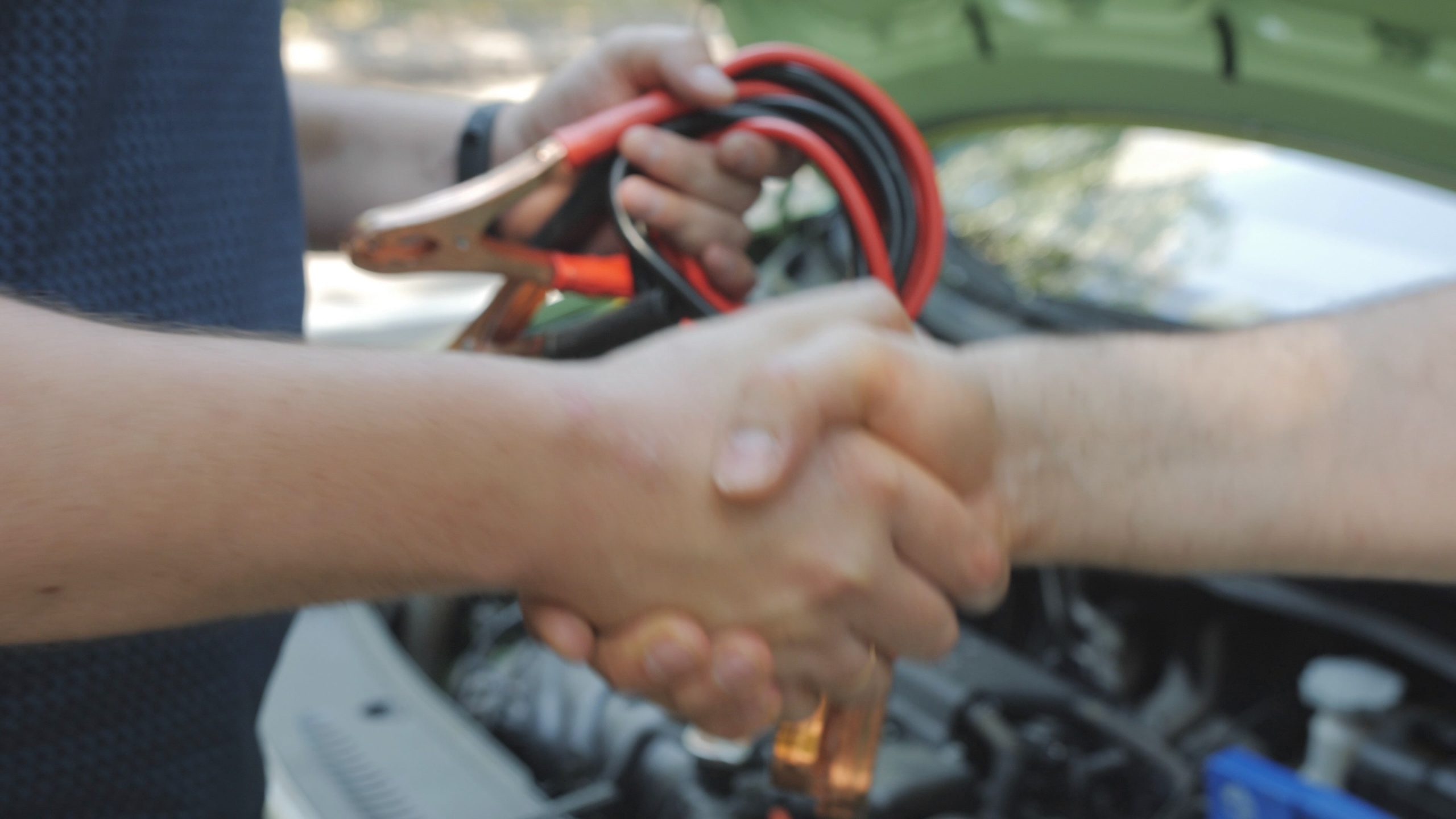 A man shakes hands with an electric vehicle owner who performed maintenance on his car